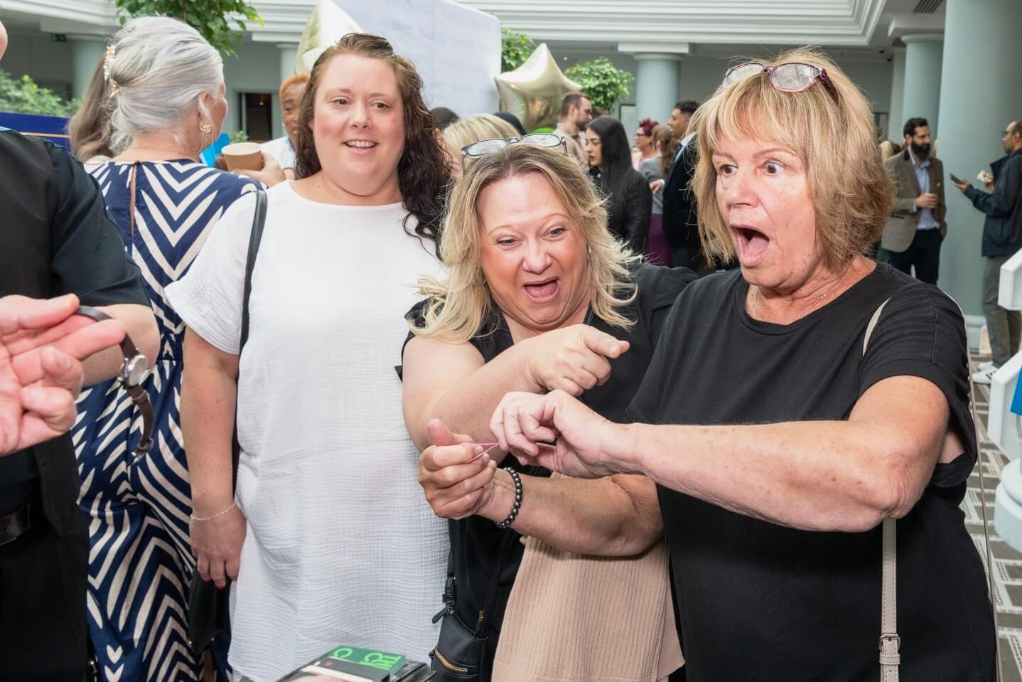 A group of guests reacting as a corporate magician reveals a woman's watch back to her